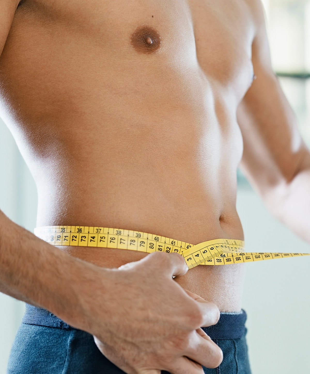 Man measuring waist with a tape measure.