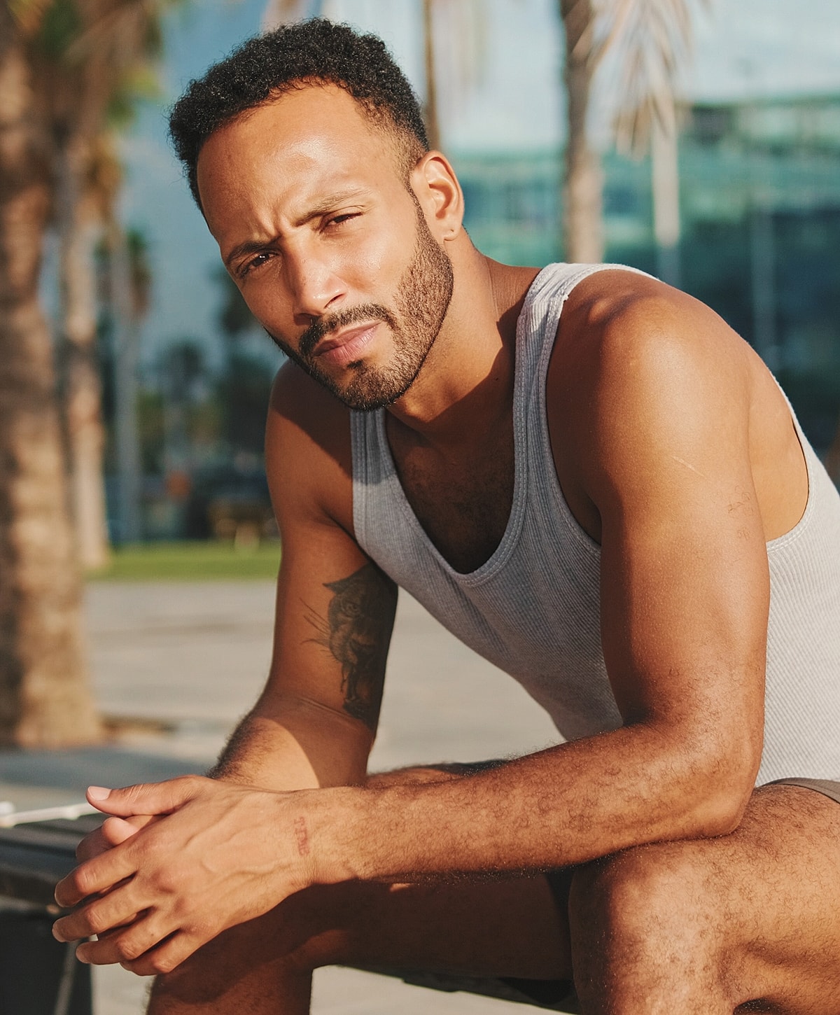 Man sitting outdoors in a tank top.
