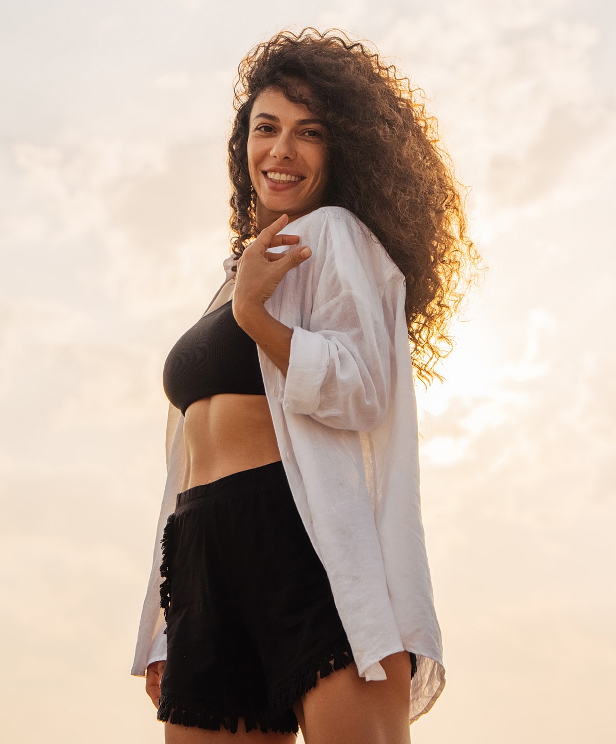 Smiling woman posing against sunset background.