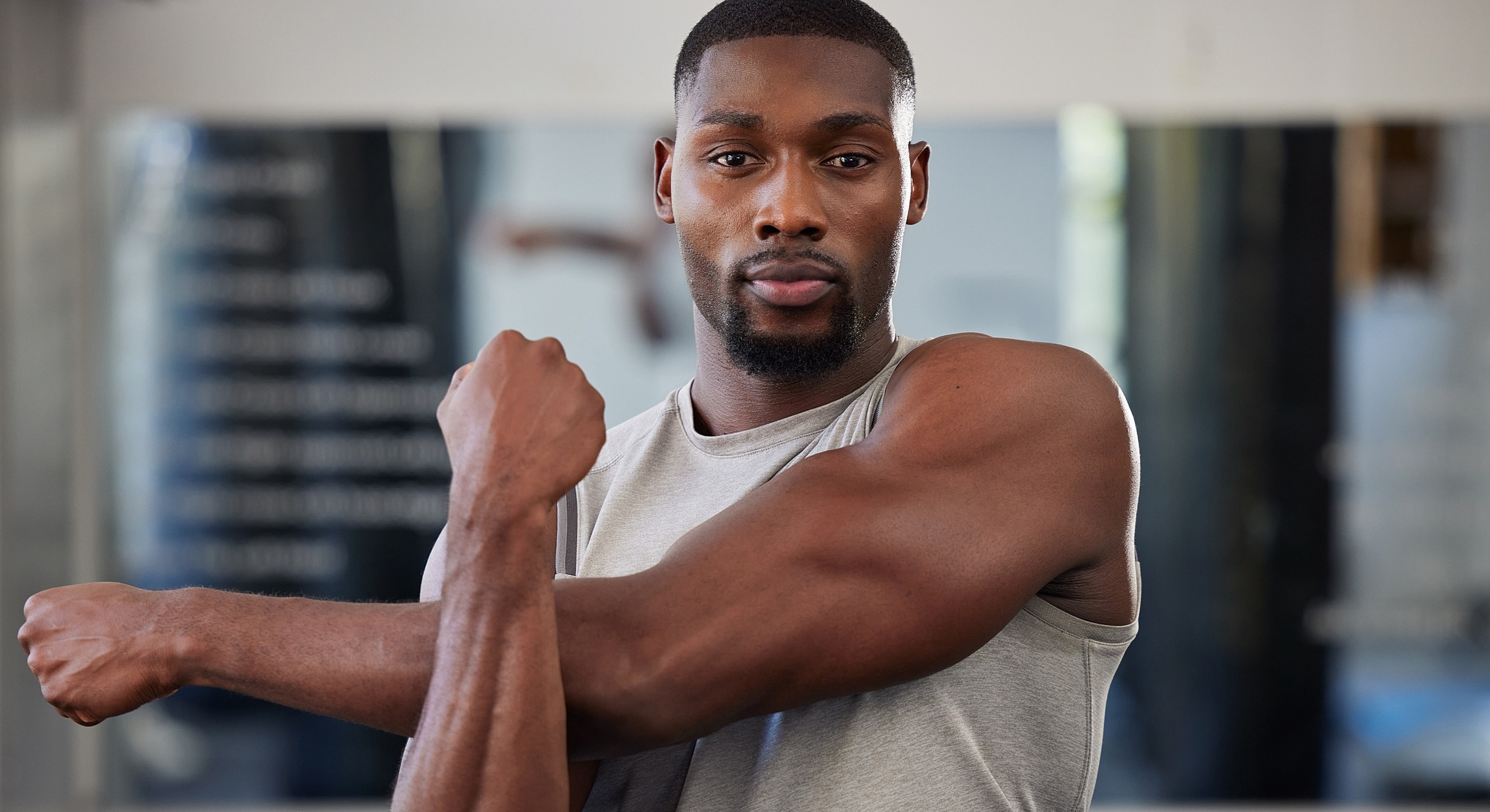 Man stretching his arm in a gym setting.