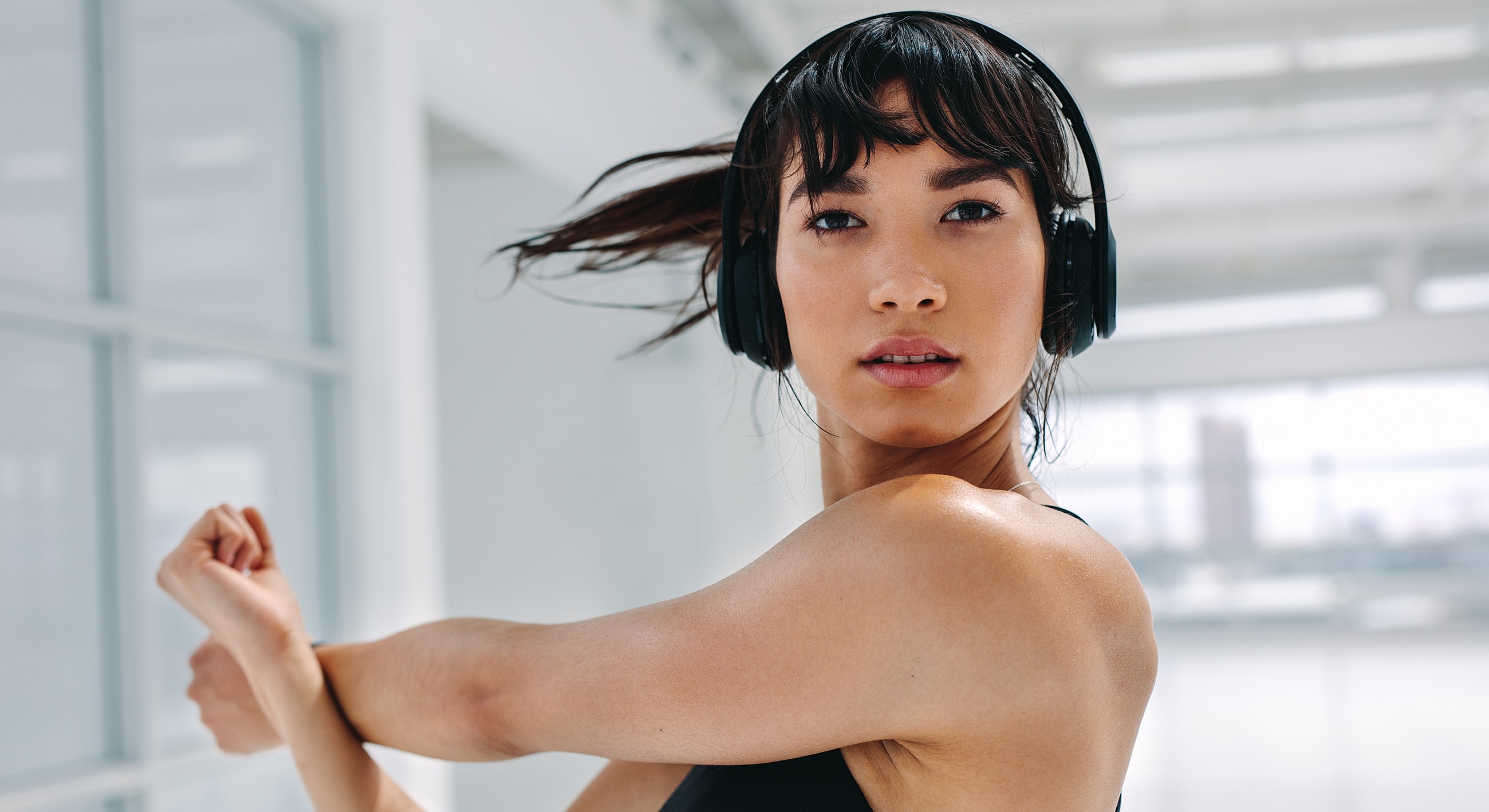 Woman stretching while wearing headphones indoors.