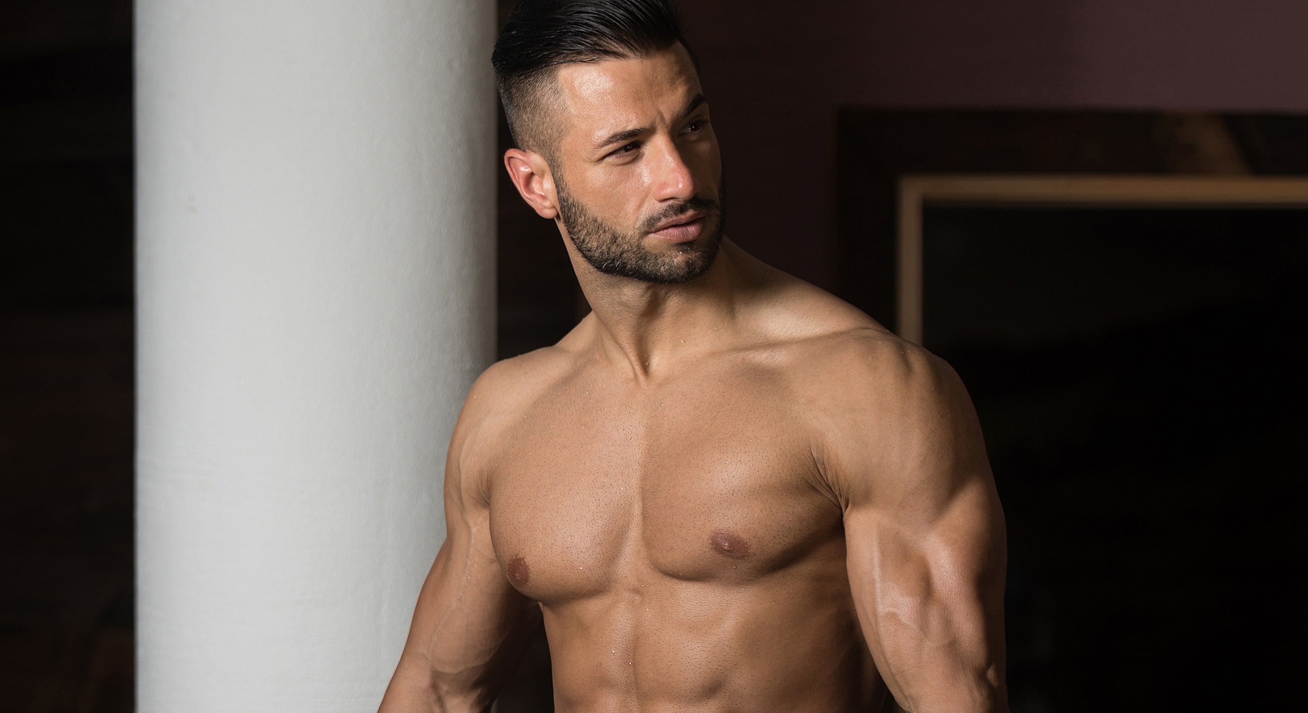 Muscular man posing indoors, stylish background.