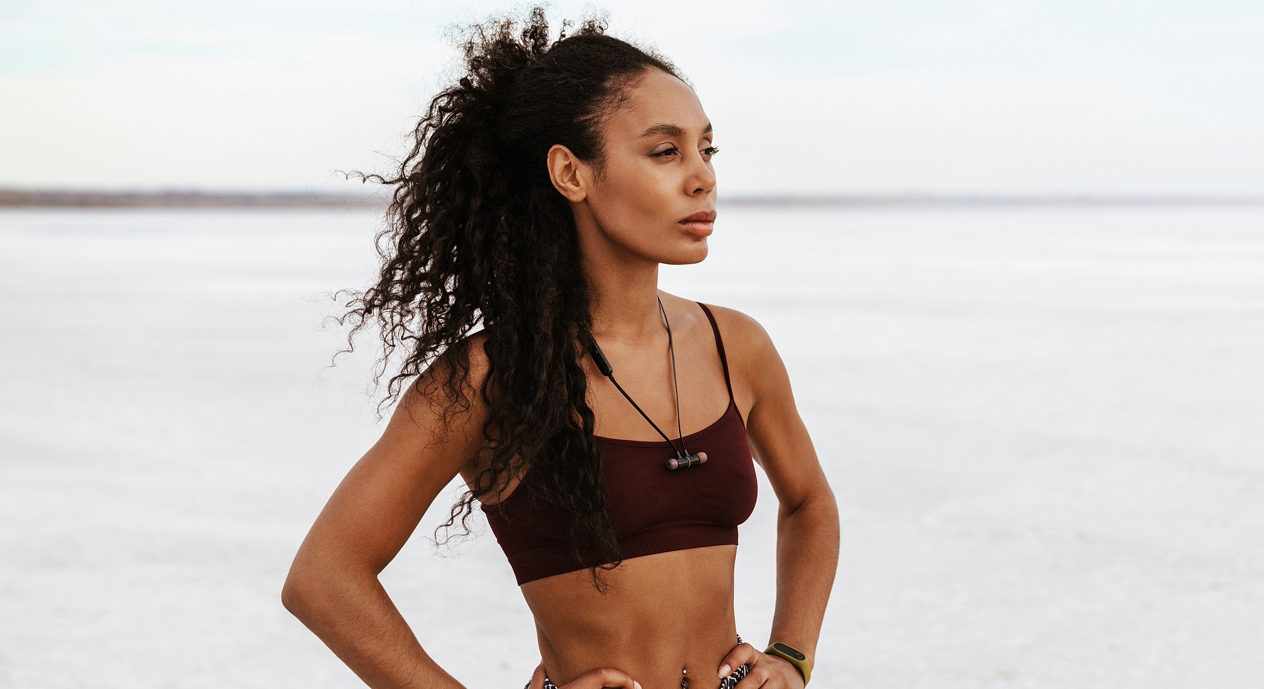 Woman with curly hair standing confidently outdoors.